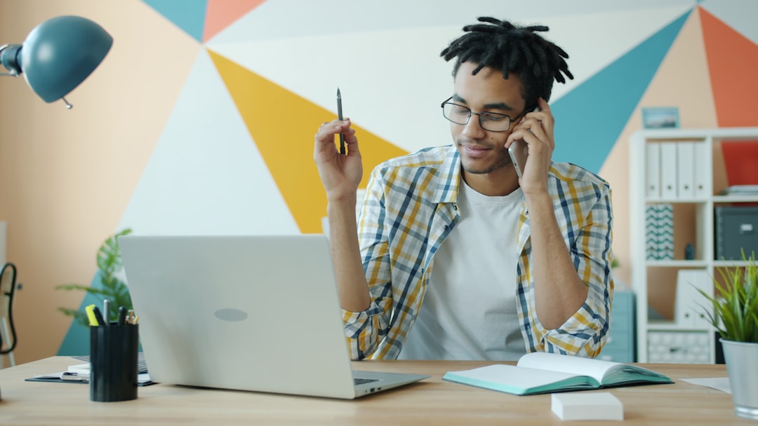 Man talking on phone at desk with laptop.